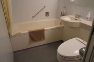 A senior woman using bathtub aids, including grab bars and a non-slip mat, demonstrating safe bathing practices.