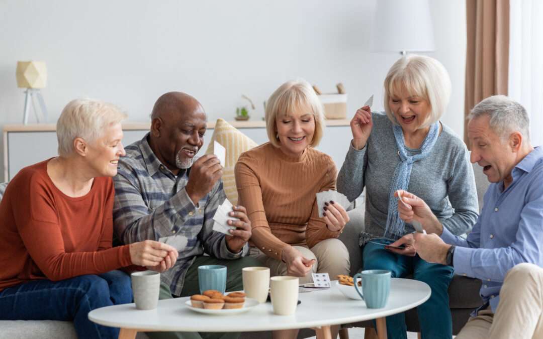 A group of seniors laughing and enjoying a card game together in a cozy living room, highlighting social interaction and fun games for seniors.