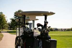 Golf cart with two golf bags filled with clubs on a sunny day, ideal for seniors enjoying a round of golf.