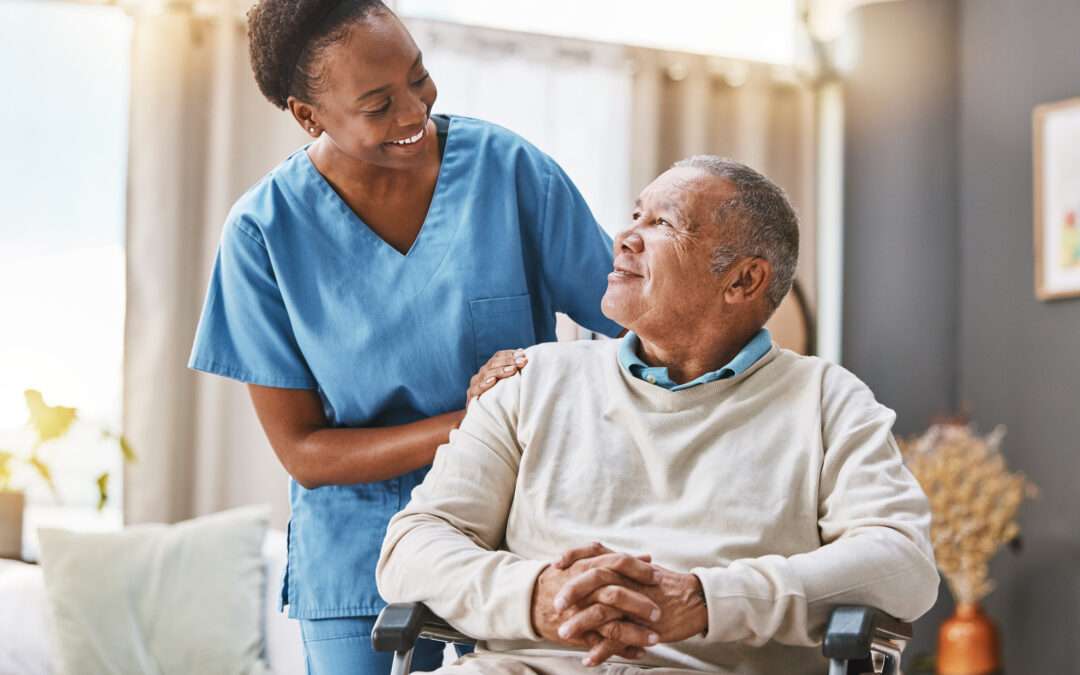 Caregiver smiling at an elderly man in a wheelchair, symbolizing compassionate elderly care.